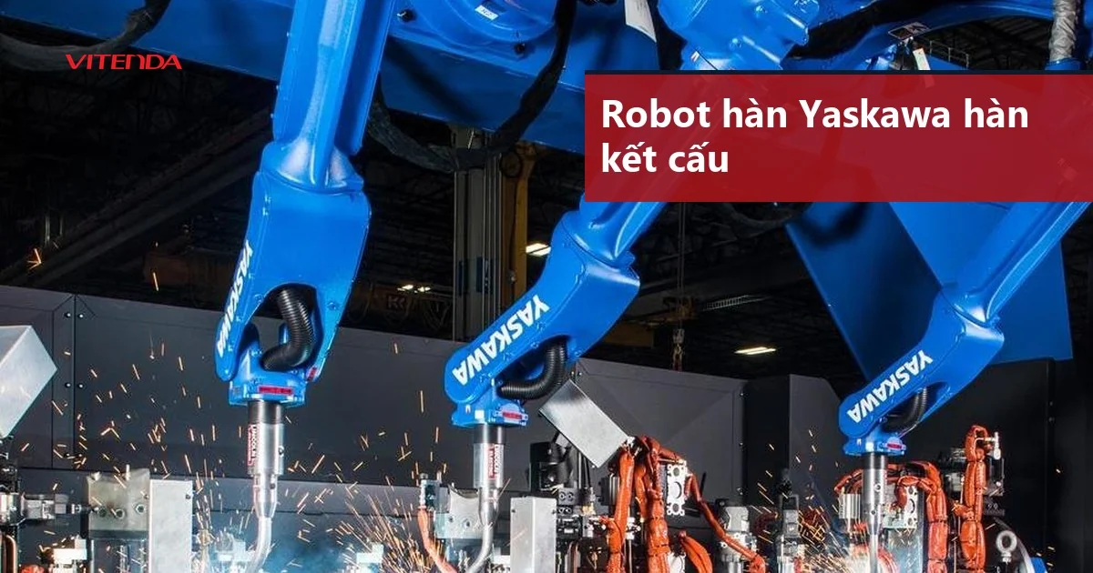 Ba cánh tay robot hàn Yaskawa màu xanh đang hàn kết cấu, tia lửa hàn bắn ra tại xưởng chế tạo