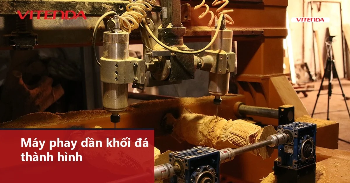 Hai đầu dao của máy CNC Vitenda đang phay dần phôi tròn, mùn cưa bám quanh bàn máy